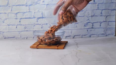 Putting almond nuts in a bowl on table