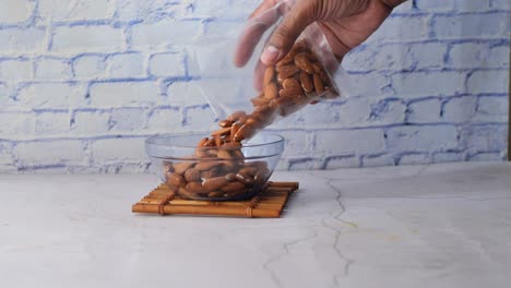 putting almond nuts in a bowl on table