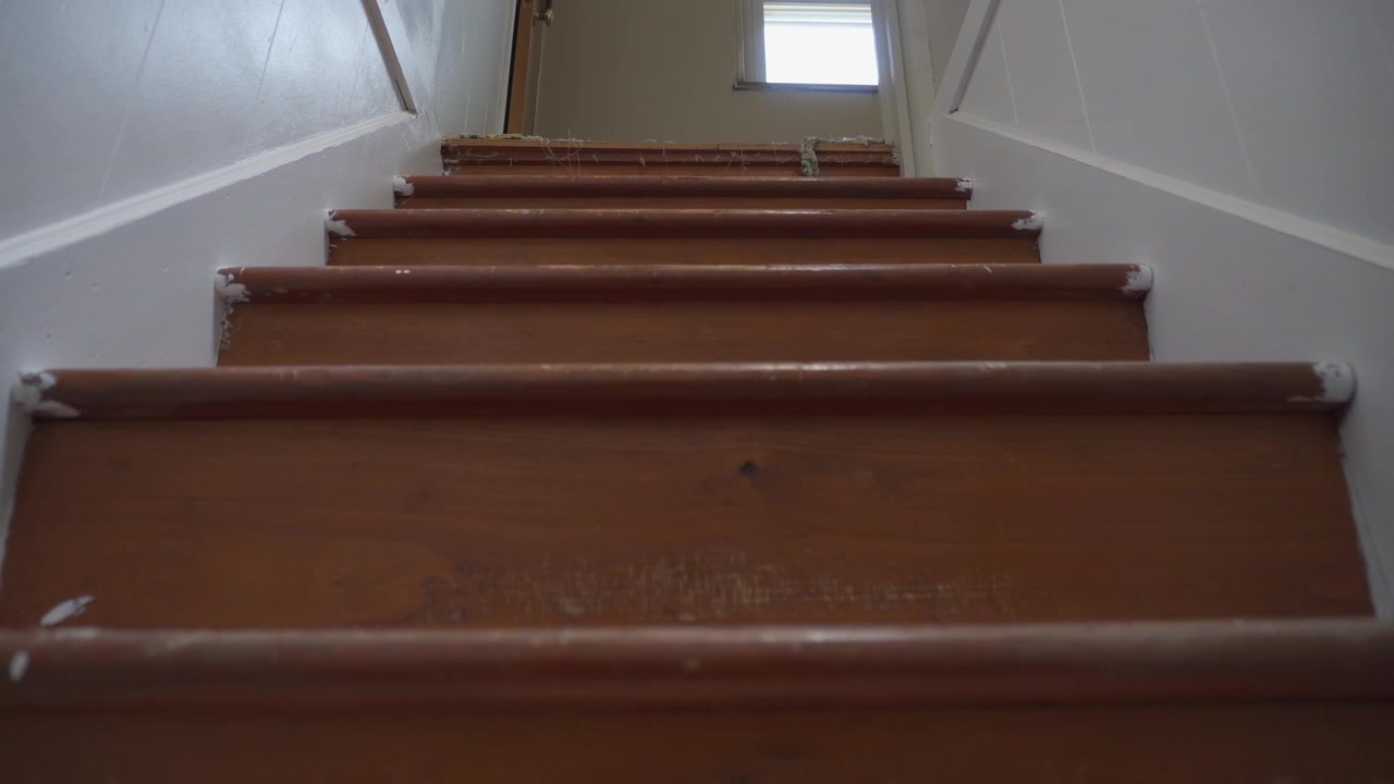 En POV-optagelse med lav vinkel og dolly, der langsomt går op ad trappen i et gammelt hjem