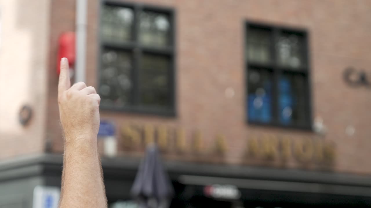 흐림 건물 배경에 대해 격리된 거리에서 파티를 하는 동안 하늘을 한 손가락으로 가리키는 남자