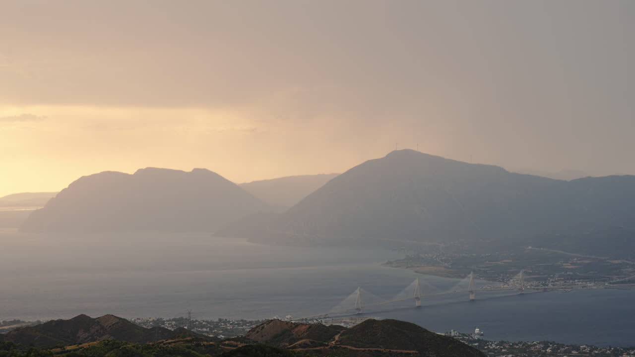 그리스 파트라 근처의 리오-안티리오 다리 위를 날아다니는 캐나다이어, 멀리 있는 산들이 안개로 사라지고 있다.