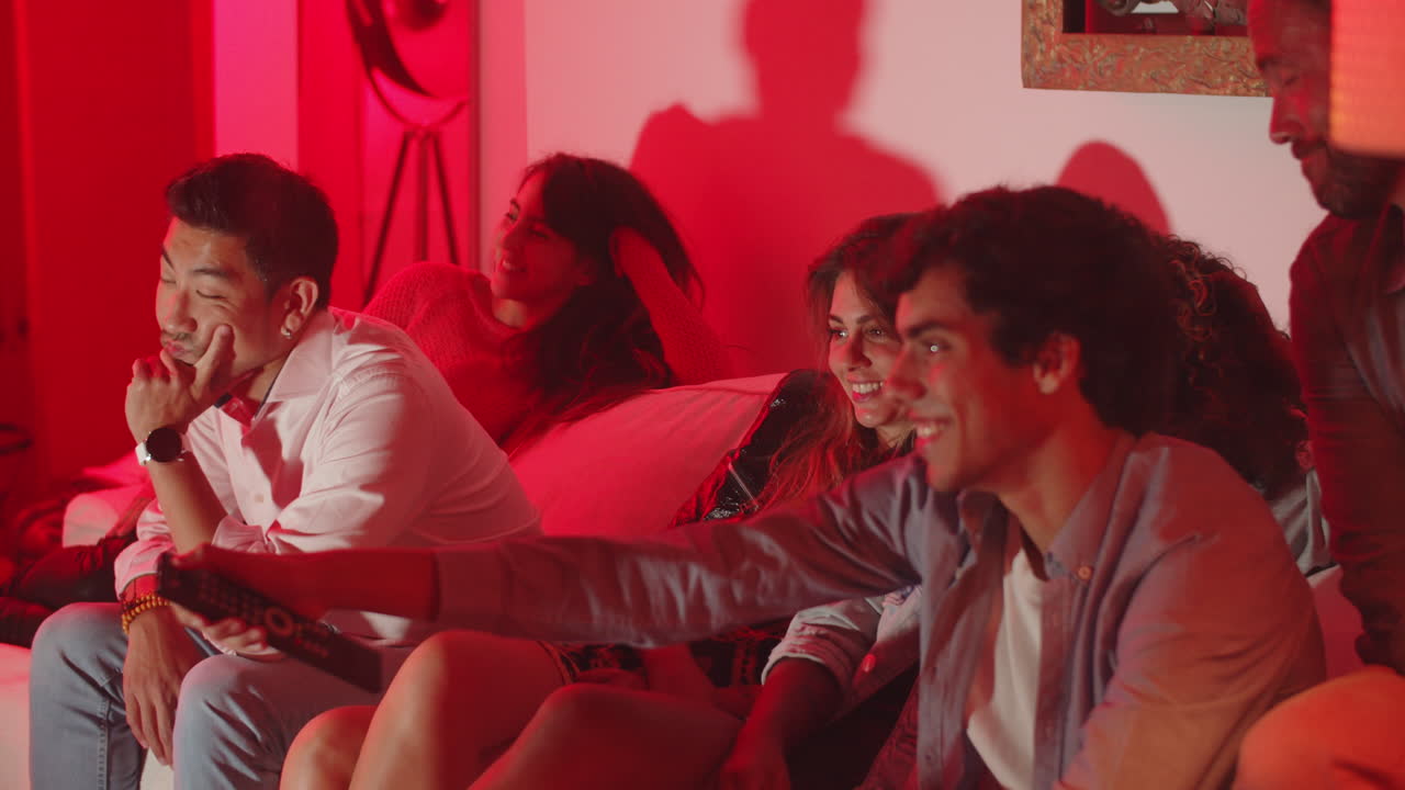 группа счастливых друзей сидит на диване и переключает каналы.