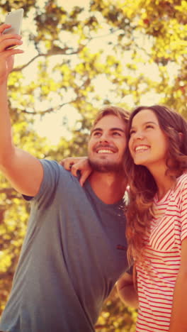 una pareja feliz tomando una selfie en el parque.