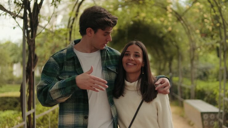 Happy young couple man and woman walk hugging inside green arch