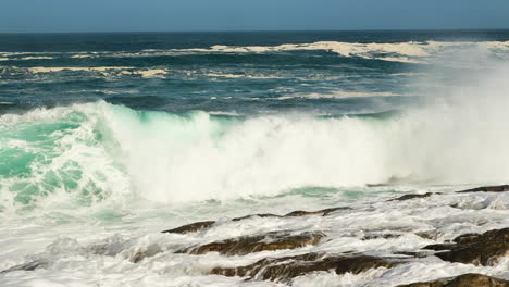 wave collides dramatically on rocky shore, big splash