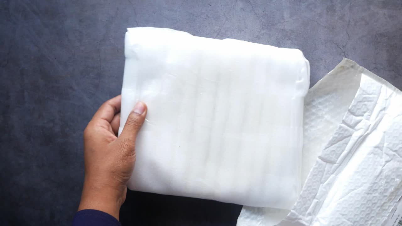 manos desempaquetando un material de embalaje protector blanco