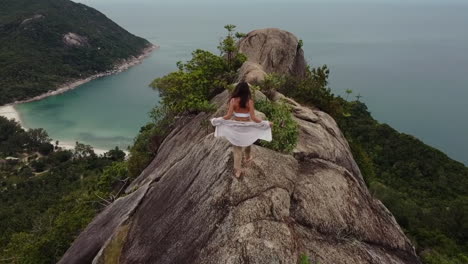 woman is walking on top of a cliff looking over the sea, majestic scenery view