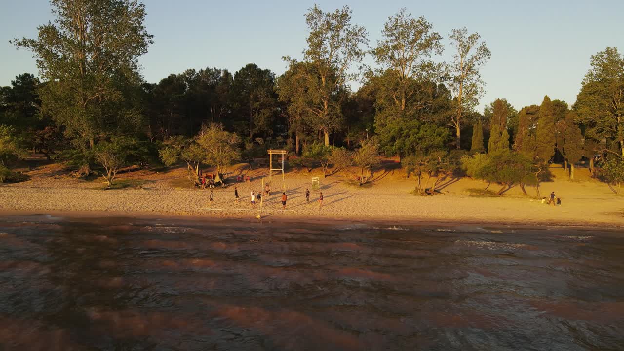 우루과이의 프레이 벤토스 해안에서 일몰 동안 비치발리볼을 하는 친구들의 드론 샷
