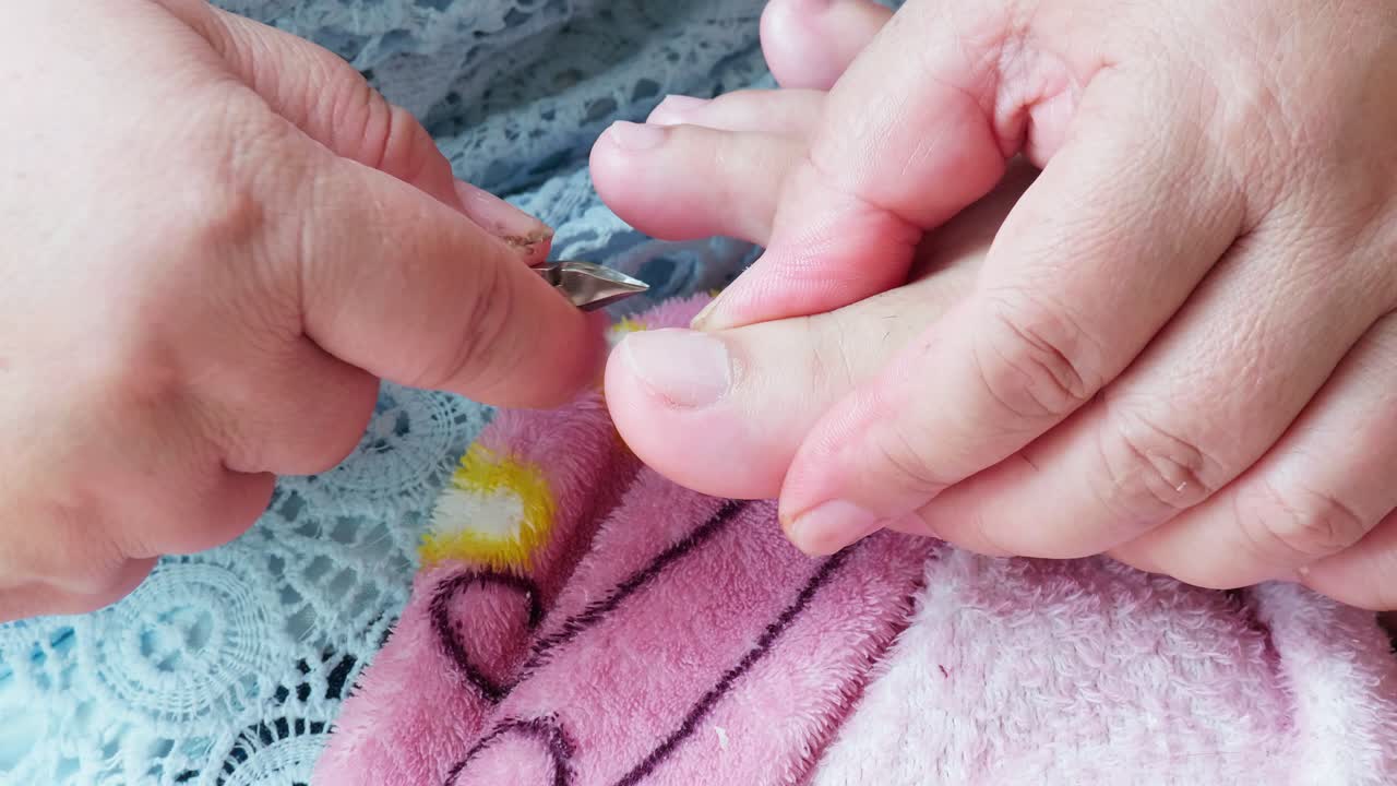 미용실-2에서 고객의 발가락에 손톱 집게로 페디큐어 절단 큐티클을 만드는 페디큐어 마스터