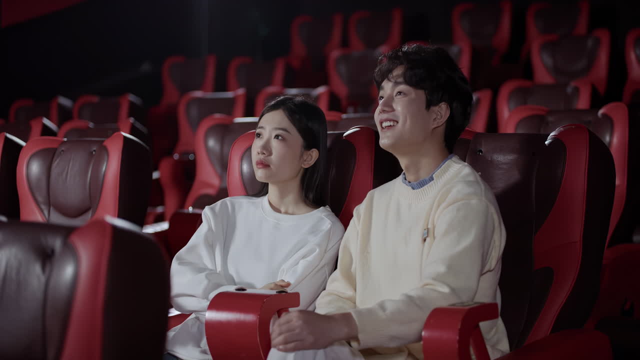 Giovane coppia di spettatori che guarda un film in un auditorium cinematografico vuoto; la ragazza annoiata, provando un'emozione negativa sgradevole, si addormenta perdendosi il film noioso, mentre il ragazzo guarda con grande interesse.