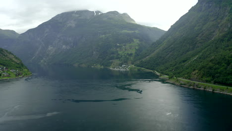 Majestätischer-Flug-Von-Geiranger-City-In-Richtung-Fjord-Mit-Leichten-Wellen,-Die-In-Richtung-Trailer-Park-Und-Møllsbygda-Fliegen