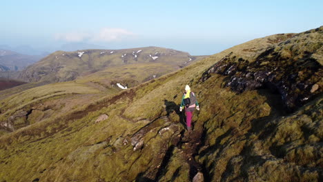 colourful hiker walking on the narrow muddy mountain patch curved out from delicate greenish moss