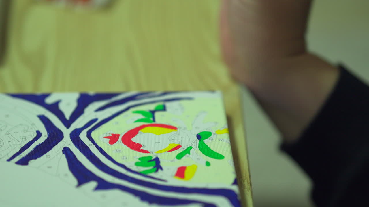 mano sosteniendo pincel de pintura mientras pinta una pintura por números lienzo