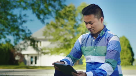 working with tablet in front of house