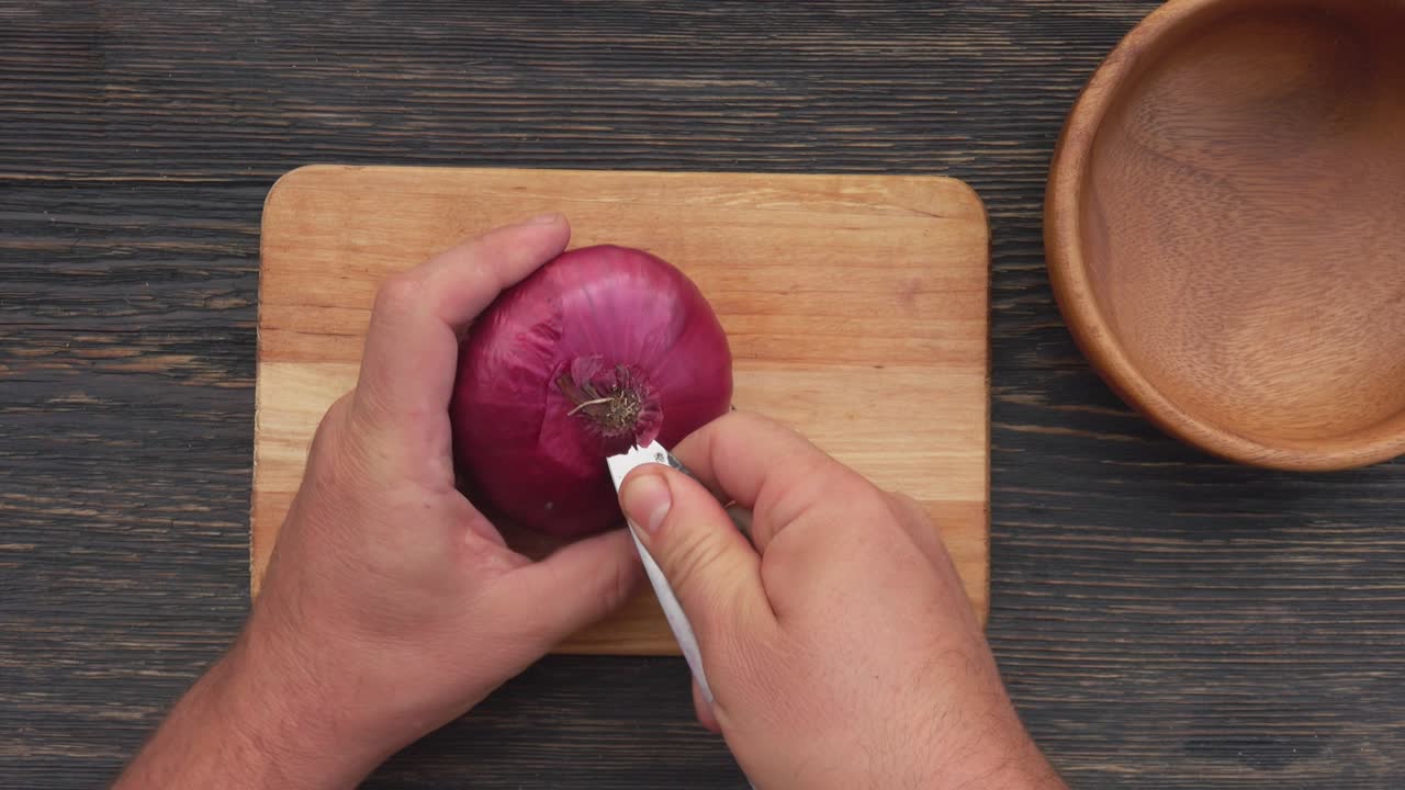 Top view of the male hand peeling onion rings with a knife