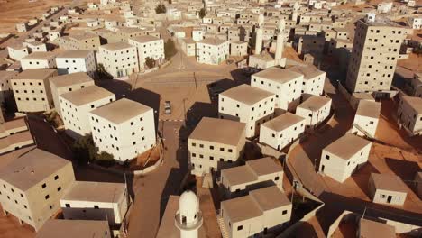 aerial shot of an old empty city in the desert in palestine near gaza at morning while camera move around the buildings and the mosques next to the main squre of the city