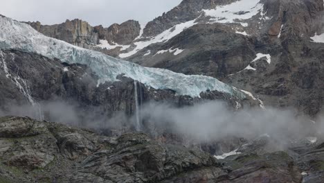 glaciar fellaria en las montañas de italia, con cascadas de agua derretida y niebla