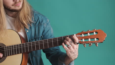 caucasian young man playing guitar on camera.