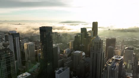 aerial of seattle skyline with bright sunbeams and low, fluffy white clouds