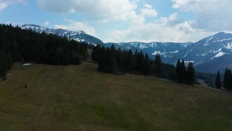 Vista-Aérea-Suave-Del-Paisaje-Montañoso-En-Entlebuch,-Suiza,-Tiempo-De-Primavera-Con-Pinos-Y-Montañas-Nevadas-Nubladas