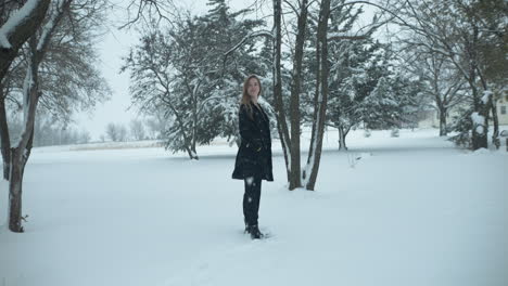 Mujer-Feliz-Afuera-En-Cámara-Lenta,-Nieve-Invernal-Navideña-Mientras-Los-Copos-De-Nieve-Caen-En-Cámara-Lenta-Cinematográfica