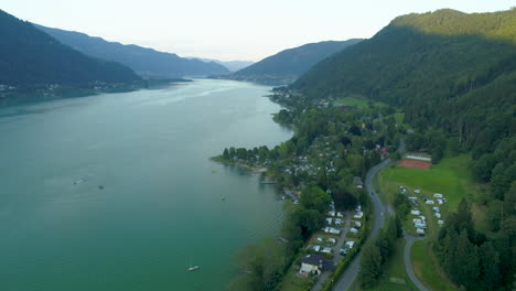 Aerial-Drone-Shot-of-Lake-Ossiach-surrounded-by-Mountains-in-Austria-during-Sunset,-Flying-forward