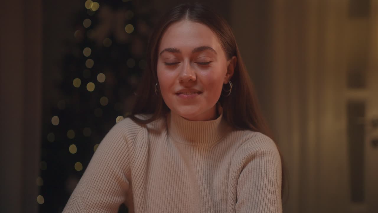 A young woman sitting near a Christmas tree