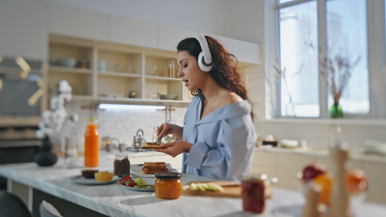 mujer relajada cocinando auriculares de pie en la cocina. niña escuchando auriculares musicales
