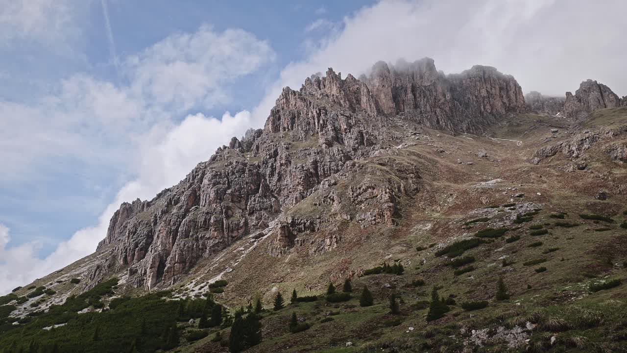 Clouds move over jagged Dolomite mountain peak in scenic sky view Low angle