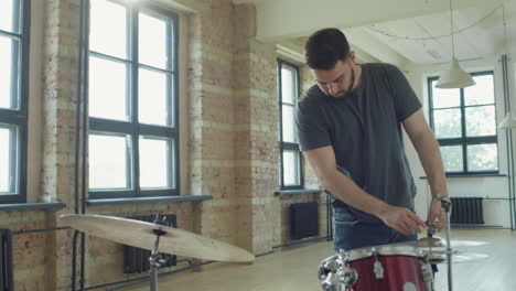 man setting up drum kit before playing