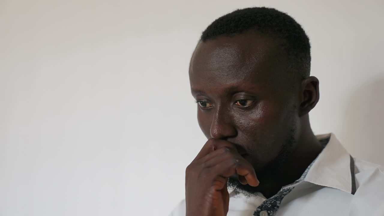 Weary man leaning against wall silently. Office worker appearing drained and overwhelmed with fatigue. Man dressed in business attire shows clear signs of extreme exhaustion and stress