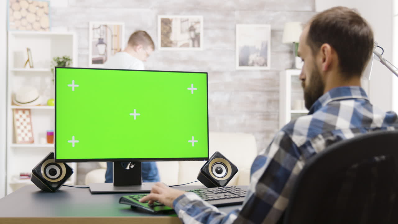 Man working at a computer with a green screen