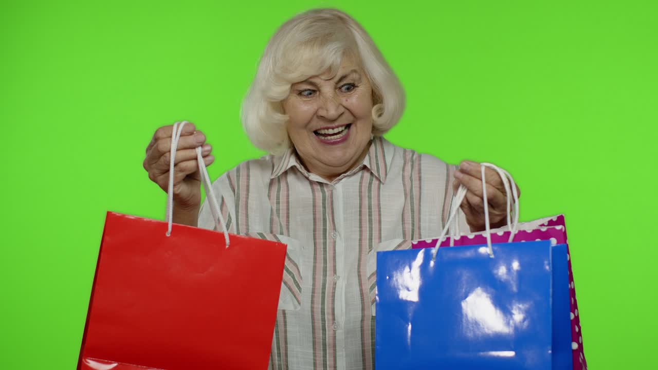 셔츠 를 입은 노인 할머니 는 쇼핑 가방 에 블랙 프라이데이 문구 를 표시 하고, 할인 을 즐기고 있다