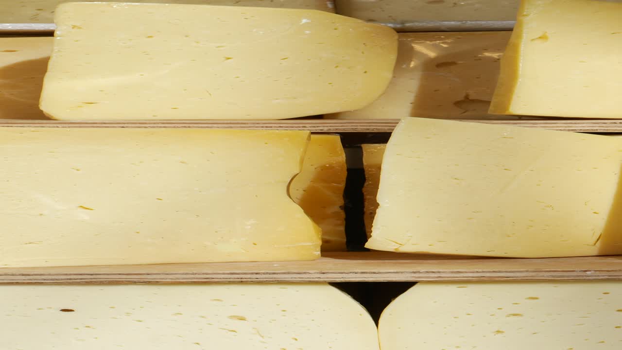 primer plano de bloques de queso amarillo en estantes de madera