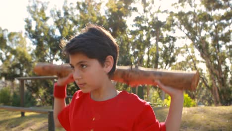 determined boy exercising with log in boot camp