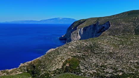 Steep-rocky-greek-coastline-in-Navagio,-aerial-orbit-on-a-sunny-summer-day