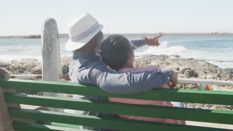 feliz pareja de ancianos afroamericanos sentados en un banco en el paseo marítimo, cámara lenta