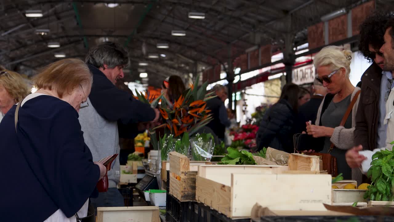People browse fresh produce and flowers at lively market in Antibes, France