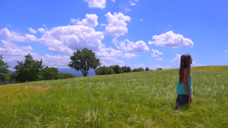 Ein-Hübsches-Junges-Mädchen-Steht-Auf-Einem-Feld-Mit-Wehendem-Wind