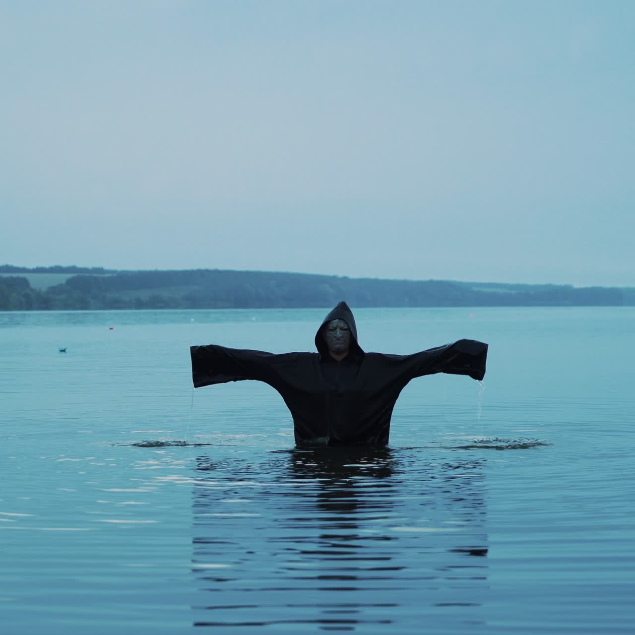 Terrible figure in a black robe in the water outdoor. Divination by Halloween