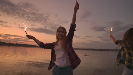 Schöne-Frauen-Im-Sommer-Mit-Wunderkerzen,-Die-Nachts-In-Zeitlupe-Am-Strand-Tanzen