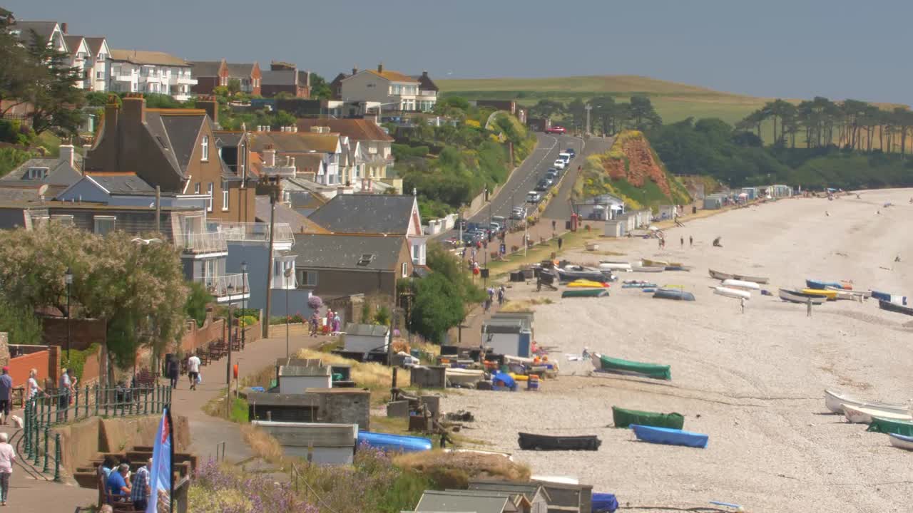 Seafront of Budleigh Salterton. Old houses, strolling people, colorful boats on the beach. Jurassic Coast, East Devon Area of Outstanding Natural Beauty, England. CROP