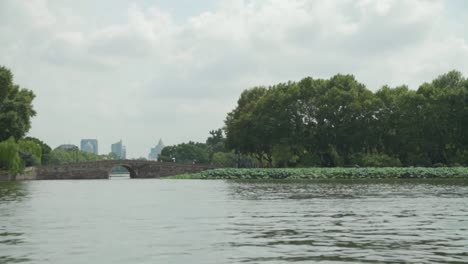 view from the west lake in hangzhou china with a bridge and the city in the background