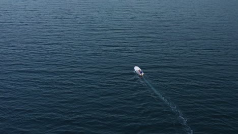 Una-Pequeña-Lancha-Blanca-Que-Cruza-Una-Amplia-Extensión-De-Mar,-Antena