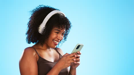 Black-woman,-phone-and-headphones-isolated-on-blue