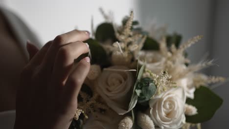 close up of hands delicately holding a wedding bouquet, highlighting soft white roses