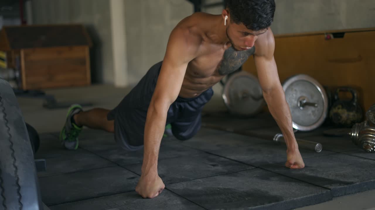 hombre musculoso concentrado haciendo flexiones en el suelo en el gimnasio subterráneo