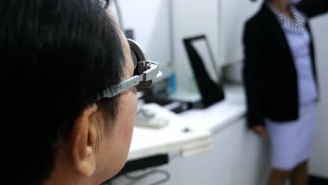 Women-at-an-optical-clinic-with-eyeglasses-used-as-an-instrument-to-test-vision-facilitated-by-a-medical-practitioner,-in-Bangkok,-Thailand