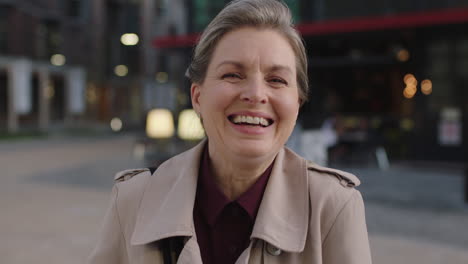 portrait of middle aged business woman laughing cheerful enjoying evening commuting in city wearing stylish coat