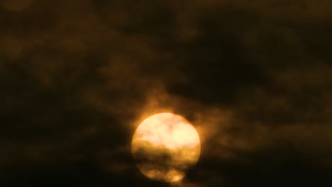 Die-Orangefarbene-Sonne-Scheint-Als-Dunkle-Wolken,-Die-über-Den-Dunklen-Himmel-Ziehen